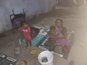 Homeless woman with her two children eating food provided during a food distribution drive in Bareilly, highlighting care and support for the needy.