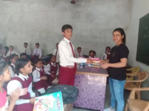 volunteer distributing books for student under sikha sabka aadhikar campaign organised by aapke saath foundation