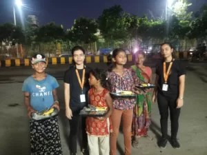 Volunteers and kids, holding food plates, smile to capture a heartwarming moment of food distribution by aapke saath foundation
