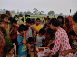 Kids lined up, waiting for their turn during a cake distribution in a Delhi slum, with Aapke Saath Foundation volunteers assisting in the event