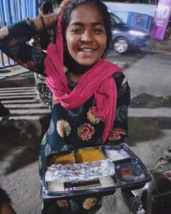 A girl enjoying a meal from the food distribution organized by Aapke Saath Foundation's 'Food for Every Breath' campaign.