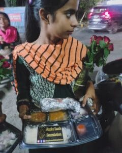 A girl enjoying a meal from the food distribution organized by Aapke Saath Foundation's 'Food for Every Breath' campaign.