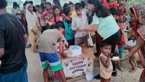 Kids lined up, waiting for their turn during a cake distribution in a Delhi slum, with Aapke Saath Foundation volunteers assisting in the event