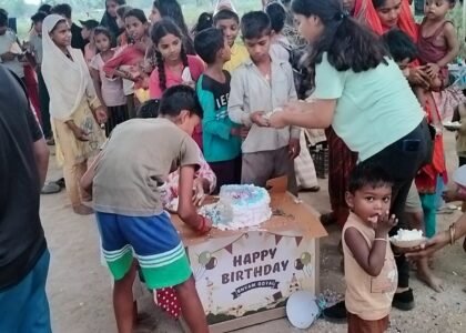 Kids lined up, waiting for their turn during a cake distribution in a Delhi slum, with Aapke Saath Foundation volunteers assisting in the event