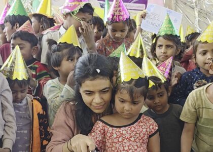 Volunteer at Aapke Saath Foundation helping underprivileged children cut birthday cake during donation birthday celebration — donate for poor children birthday, sponsor a birthday for needy kids, celebrate birthday with slum children