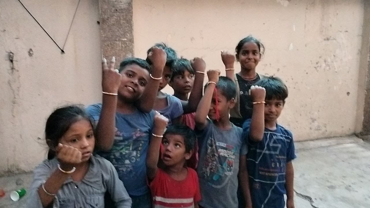 Group of slum children showing Rakhis tied by volunteers during Raksha Bandhan NGO donation campaign