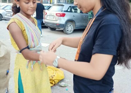 NGO volunteer tying rakhi to slum girl during Raksha Bandhan 2025 festival donation campaign in India