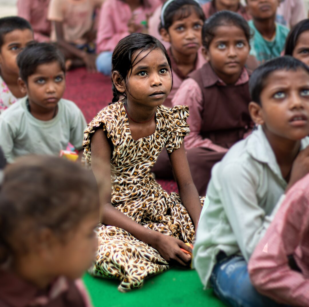 underprivileged girl studying with other children through NGO education support program in India